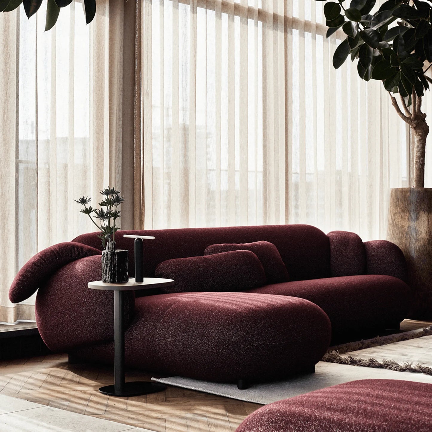 Modern living room with Leolux Pulla Sectional sofa in burgundy red fabric with a side table.