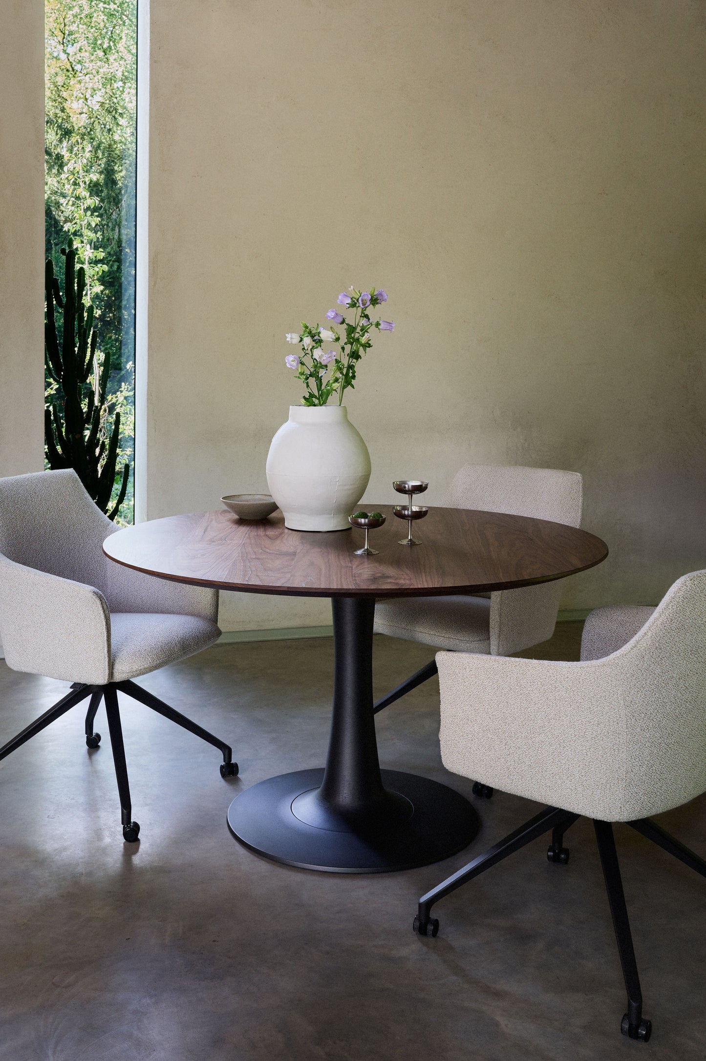 Leolux columna Round wooden walnut table with column base in a modern room.