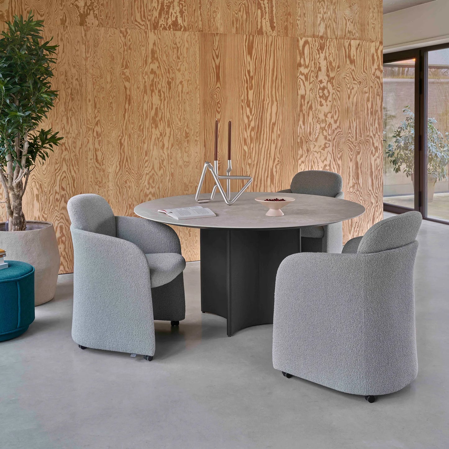 Leolux Conka Round Dining table with ceramic top and leather base in a minimal modern dining room with wood walls