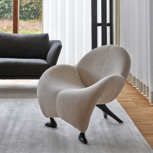 Leolux Papageno Lounge Chair in Beige boucle fabric in a modern living room with a gray sofa and large windows.