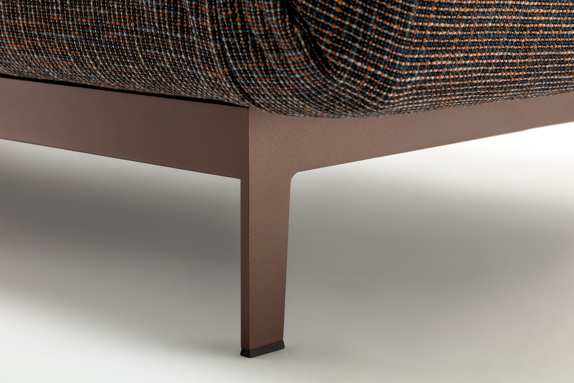 Close-up of a brown upholstered Rolf Benz Mera sofa with a textured fabric on a light background