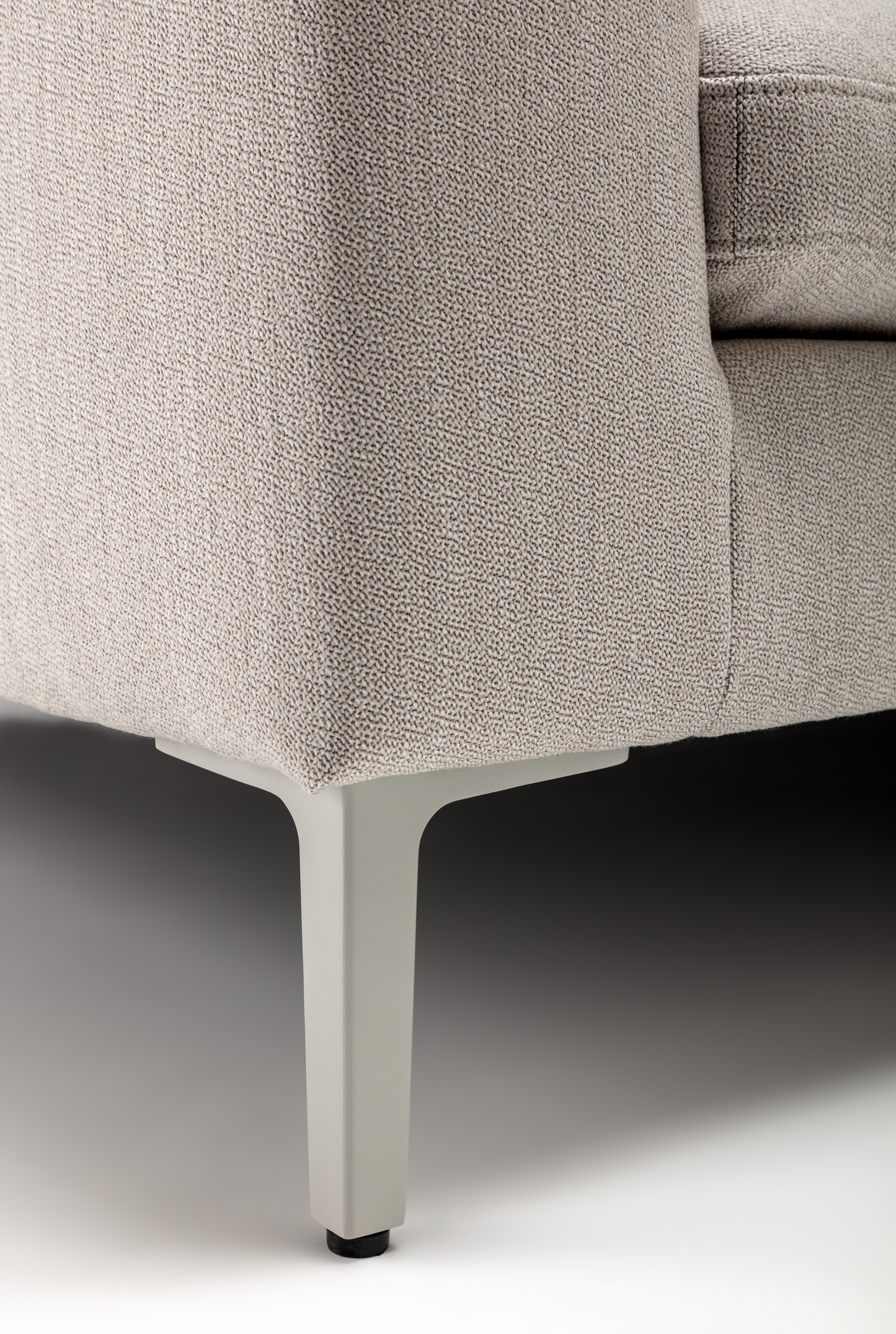 Close-up of a textured gray sofa corner with a neutral background